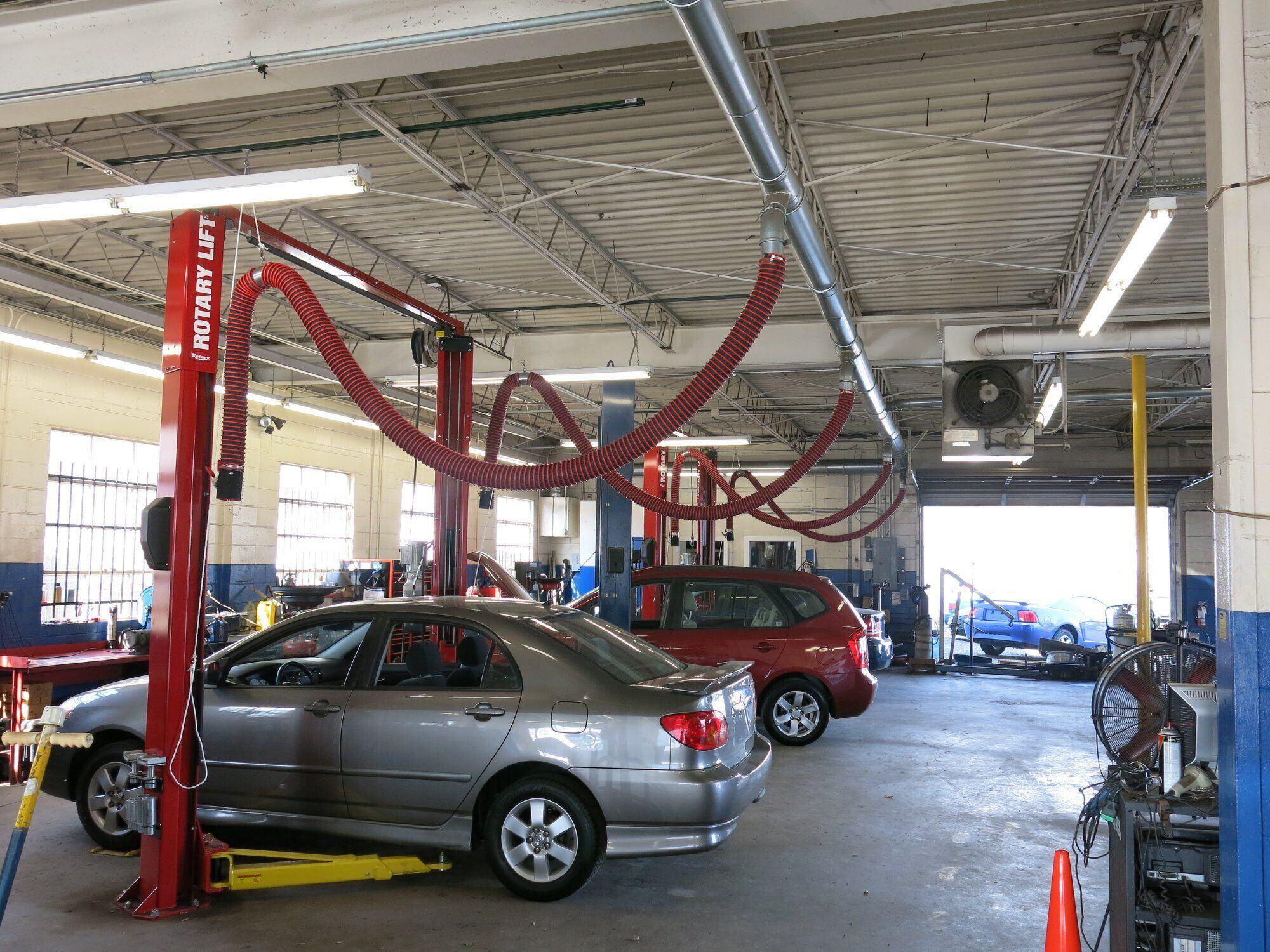 Vehicles shown in a repair and maintenance facility with overhead exhaust extraction systems installed at each bay.