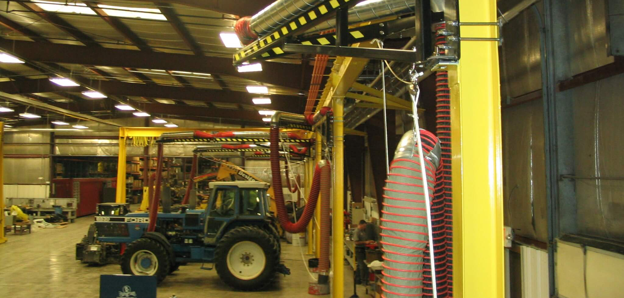 Boom arm exhaust hose extended 25 feet over tractor engine capturing diesel fumes at repair facility