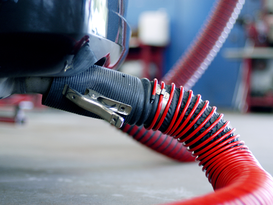Fume-A-Vent tailpipe adapter shown connected to hose and passenger vehicle to remove exhaust.