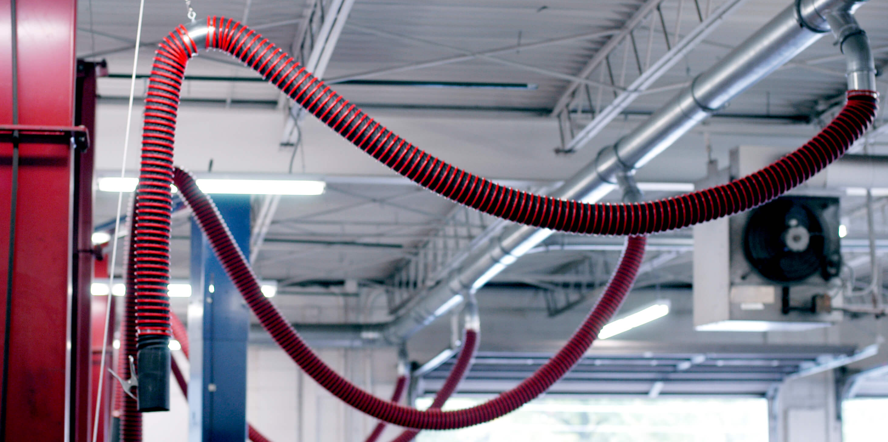 Fume-A-Vent rope and pulley hose system retracted overhead keeping auto shop floor clear and safe